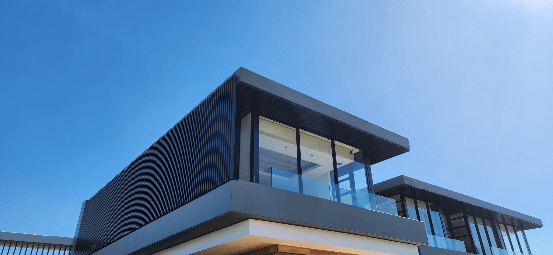 Ground floor angle looking up at home with glass, aluminum doors, and balustrades - alufox